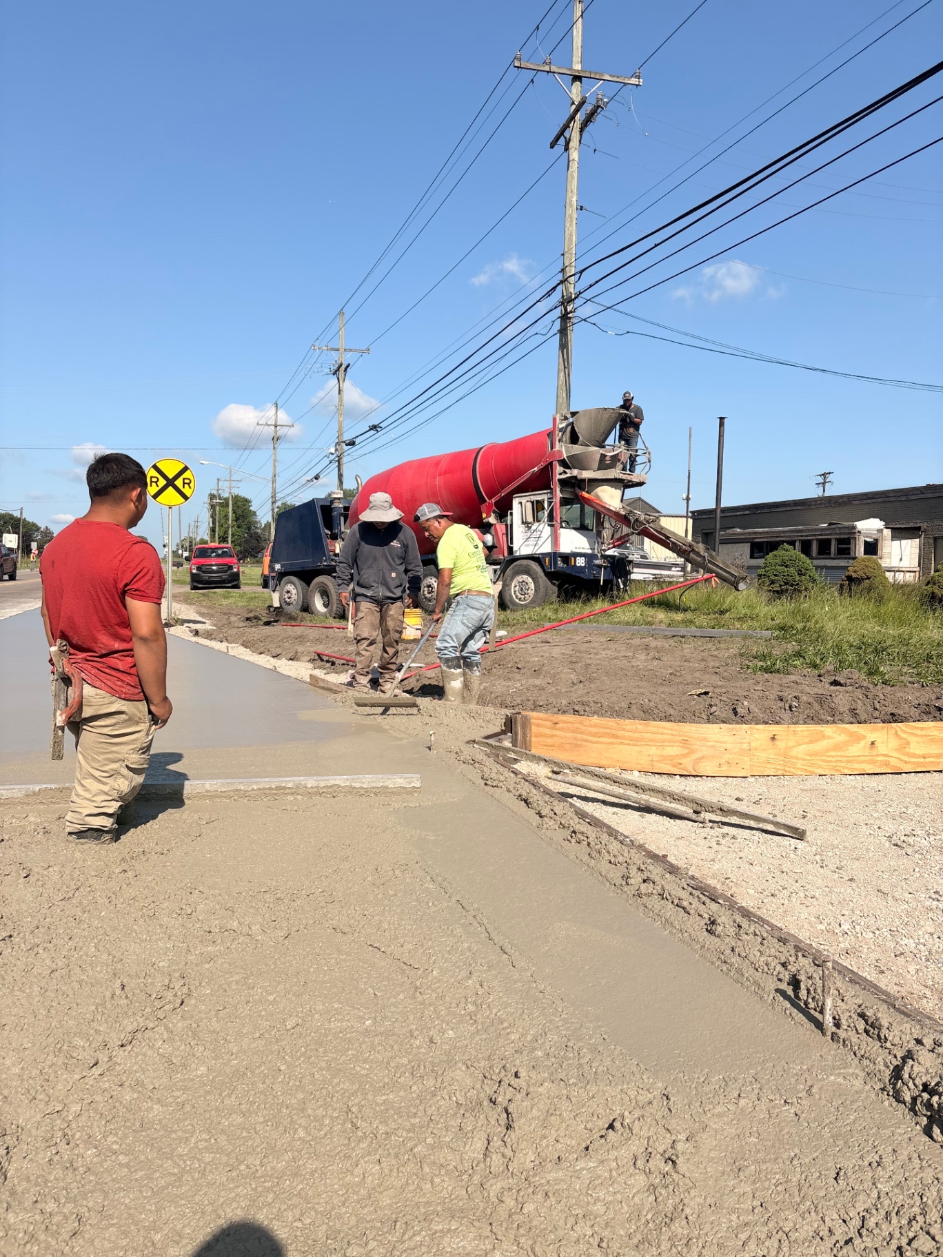 Concrete crew finishing a sidewalk pour next to a mixer truck